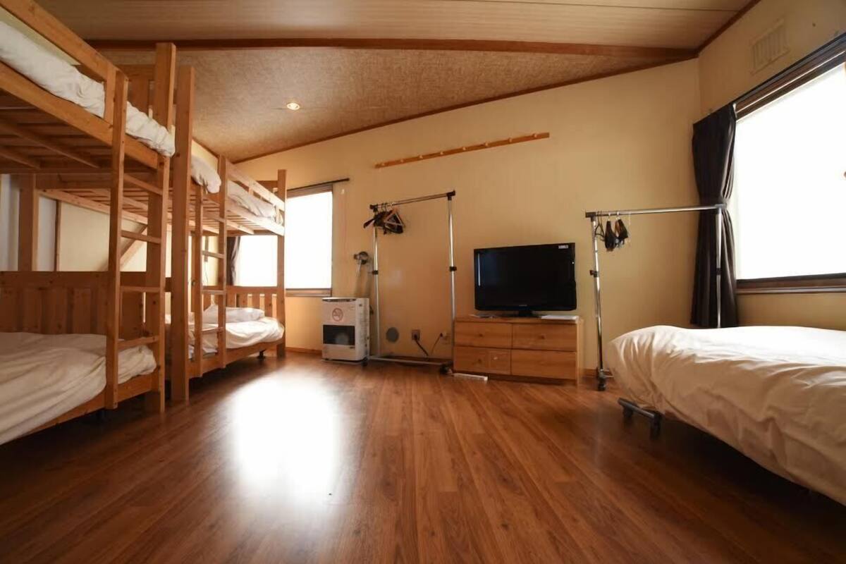 A room with bunk beds, a television, a heater, and a window.