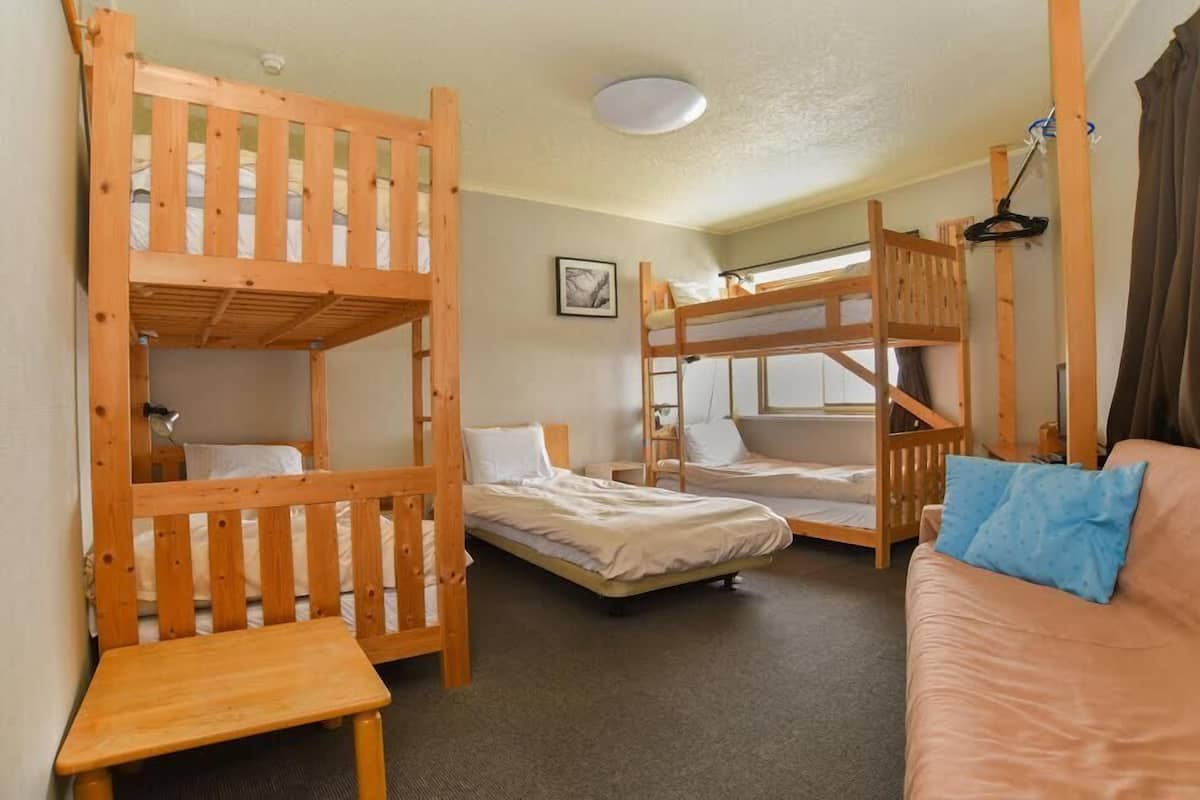 A room with bunk beds, a sofa, and a small table.