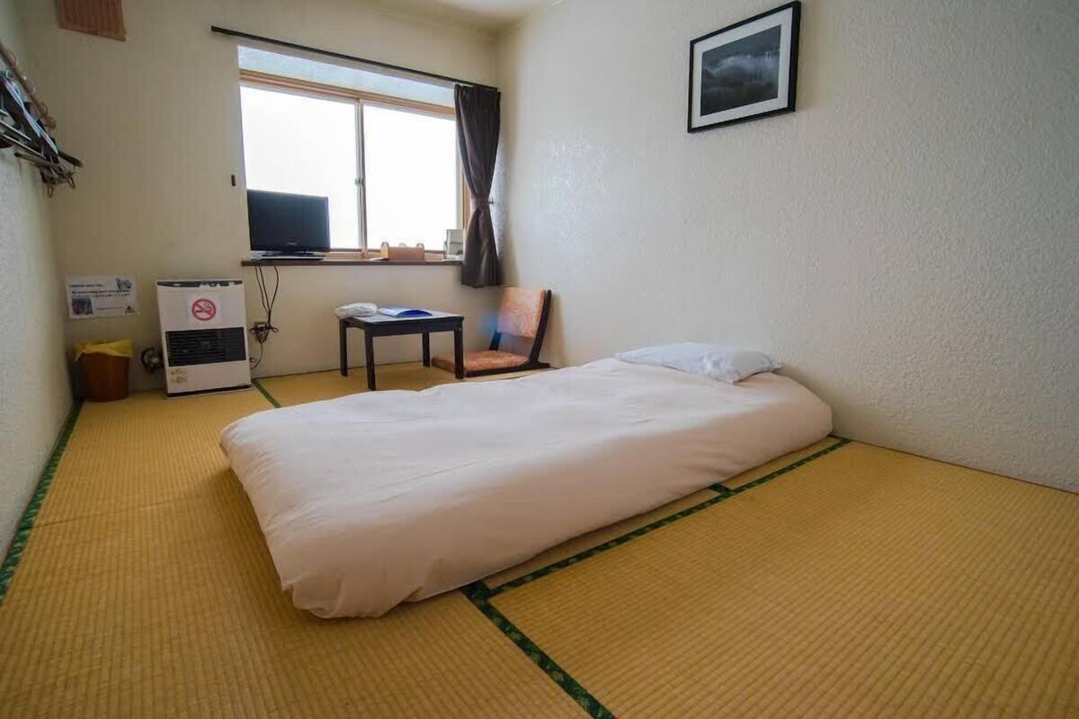 A hotel room with a bed, a chair, a desk, and a window.