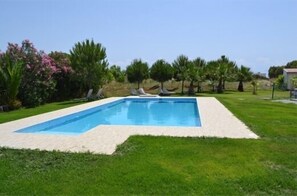 Una piscina al aire libre, sombrillas, sillones reclinables de piscina