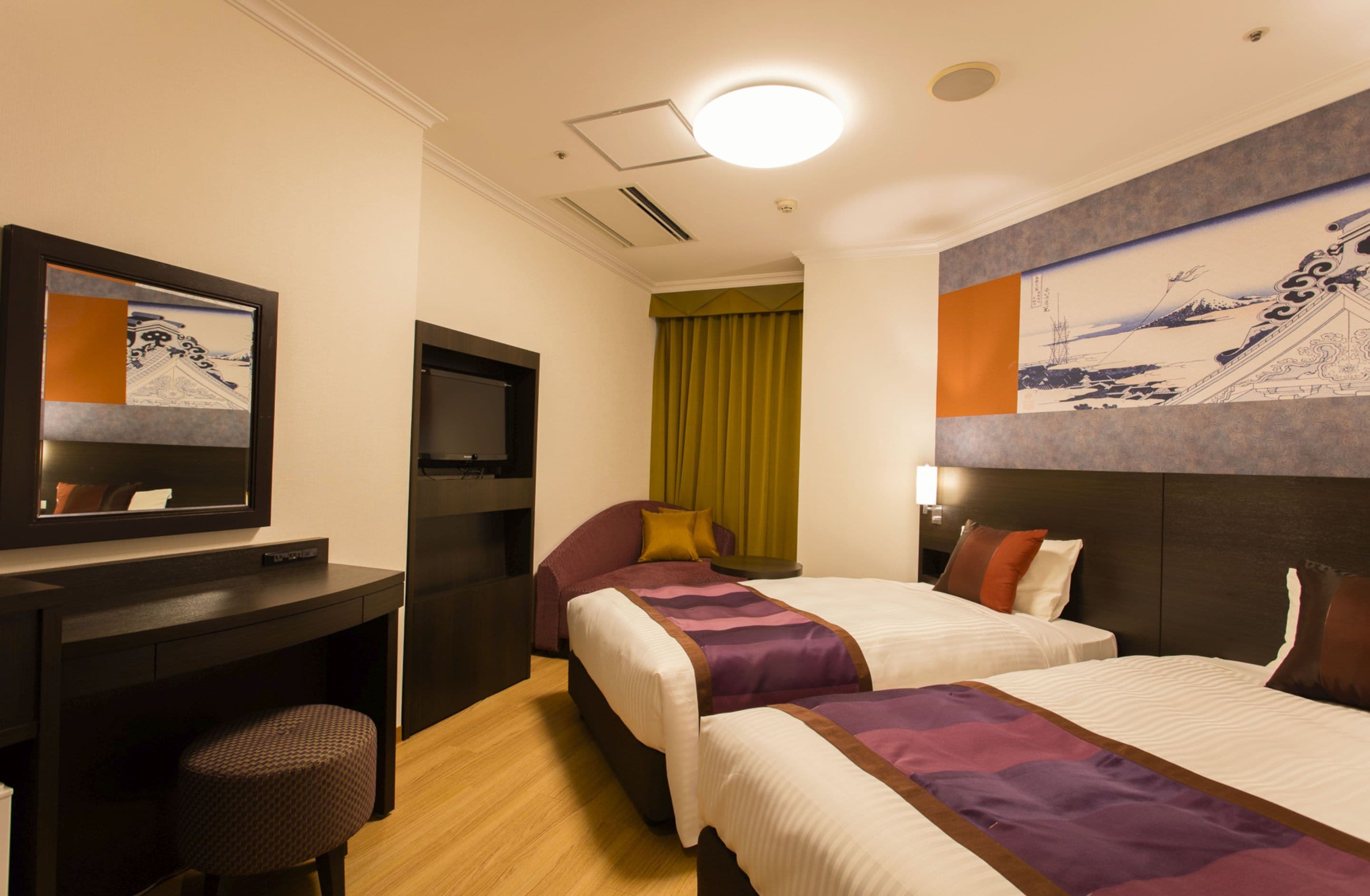 Une chambre d’hôtel avec deux lits, un bureau, une chaise, une télévision et un tableau au mur.