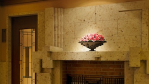 A lobby with a stone fireplace, a bench, and a floral arrangement. - Ryogoku View Hotel (Tokyo)
