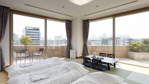 A hotel room with two beds, a dining table, chairs, and large windows offering a city view. - Ryogoku View Hotel (Tokyo)
