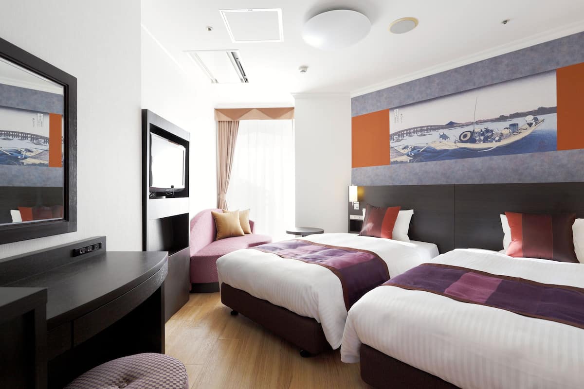 A hotel room with two beds, a TV, a desk, and a large painting on the wall.