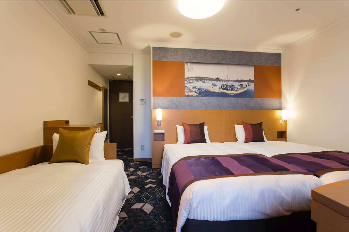 A hotel room with two beds, a large painting on the wall, and a carpeted floor.