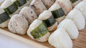 A tray of sushi rolls with rice and seaweed on a wooden board.