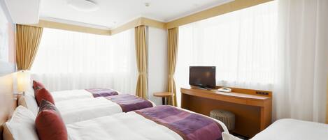 Habitación de hotel con dos camas, un escritorio con televisor y una ventana con cortinas.