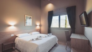 Een slaapkamer met een bed, nachtkastjes, een bureau en een raam met gordijnen.