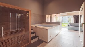 Een moderne badkamer met een douche met glazen wand, een ingebouwd bubbelbad en uitzicht op de omgeving.