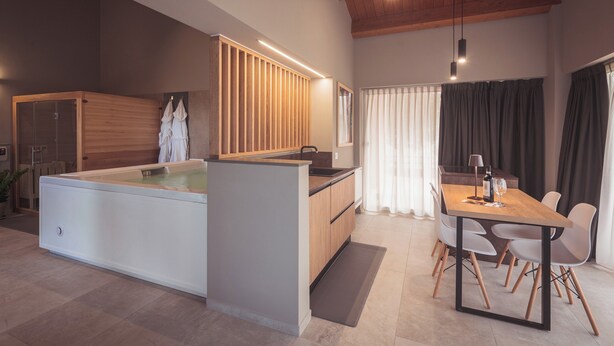 Een moderne keuken met een centraal eiland, houten kastjes en een eethoek met een tafel en stoelen.