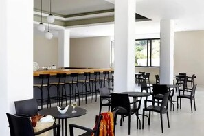 A modern dining area with high ceilings, a long bar, and multiple seating arrangements. - Evita Resort (Rhodes)