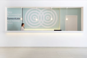 Un área de recepción de diseño moderno, con una pared grande con un motivo circular y un cartel que promociona la conectividad WiFi.