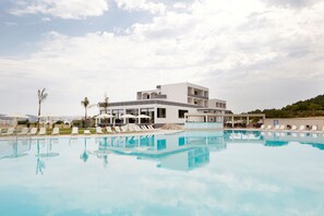 A modern hotel with a pool, lounge chairs, and umbrellas. - Evita Resort (Rhodes)