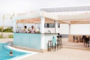 Un bar junto a la piscina con mostrador, taburetes y una piscina.