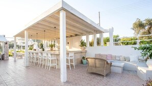 A covered outdoor area with a bar, seating, and potted plants. - Evita Resort (Rhodes)