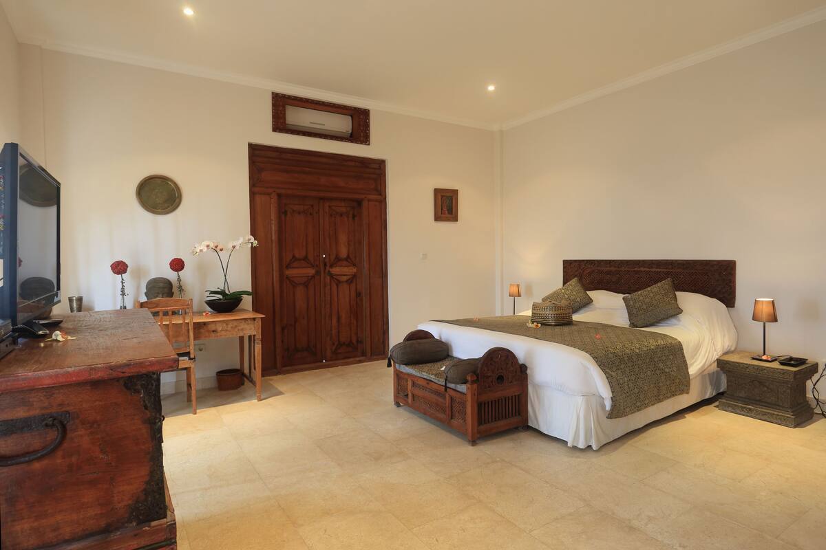 A bedroom with a wooden bed, bedside table, and a desk with a chair.