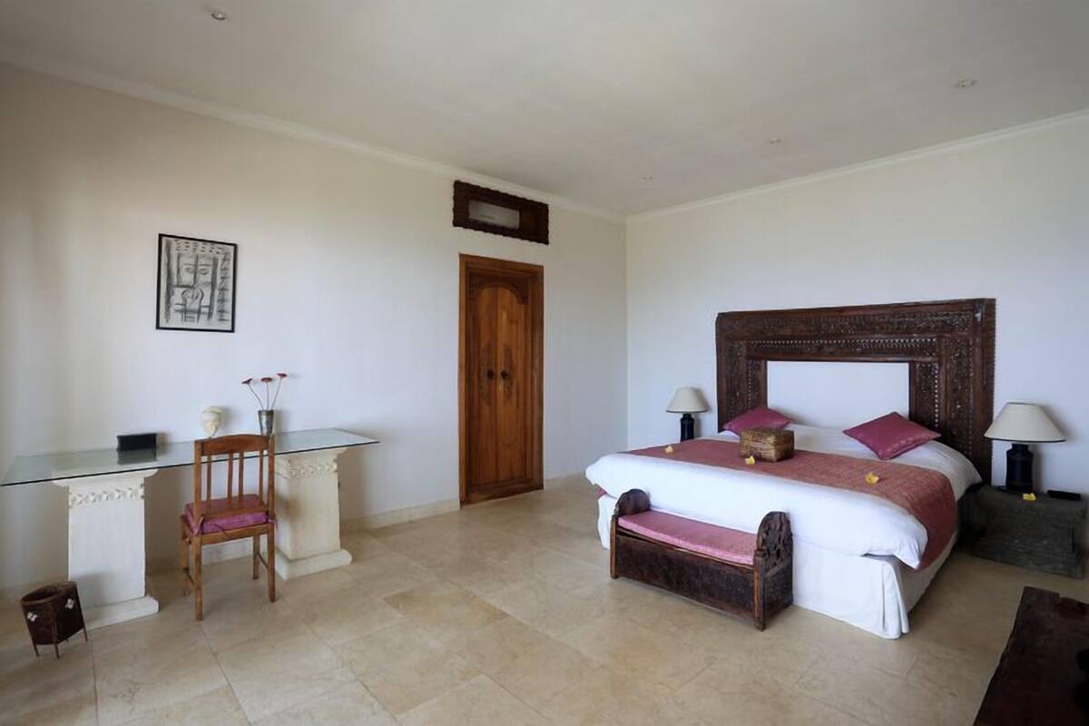 A bedroom with a bed, bedside tables, a desk, and a chair.
