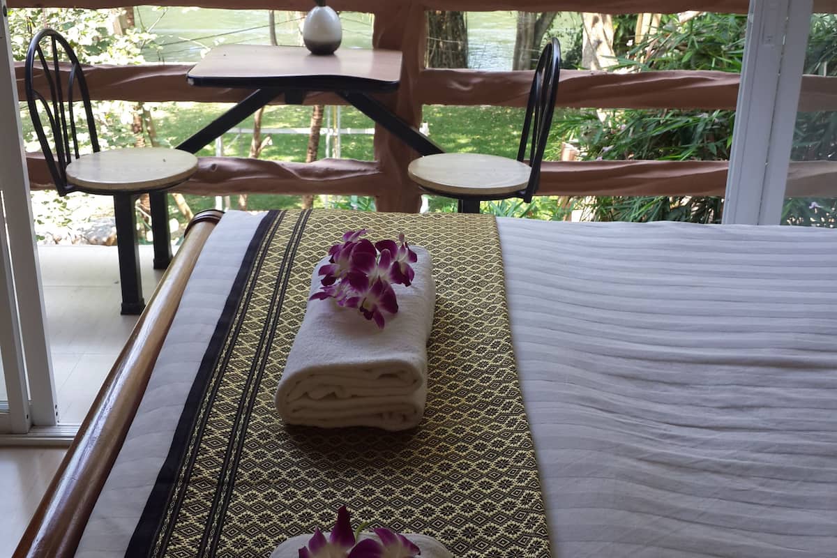 Una habitación con cama, dos sillas, una mesa y vistas a un jardín exuberante.