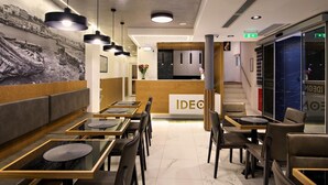 A modern restaurant with a reception area, wooden tables, and black chairs. - Ideon Hotel (Chania)