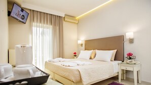 A hotel room with a bed, bedside table, and a TV mounted on the wall. - Ideon Hotel (Chania)