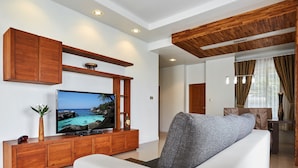 A modern living room with a flat-screen TV, wooden entertainment unit, and a white sofa. - NB Villa Vimana (Koh Samui)
