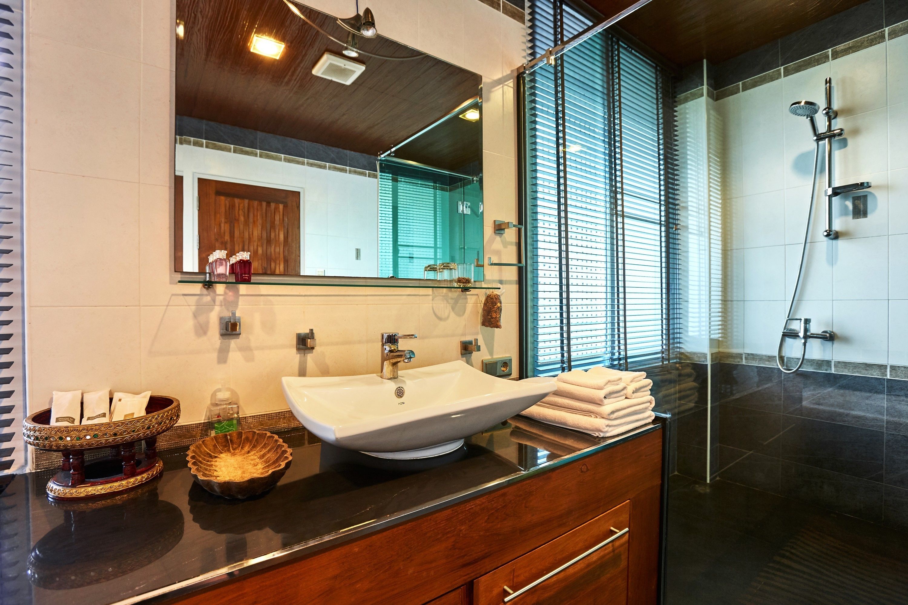 A modern bathroom with a large mirror, a vessel sink, and a glass-enclosed shower.
