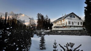 A hotel with a modern design, a snow-covered landscape, and mountains in the background. - Apartmány Belveder (Vysoké Tatry)