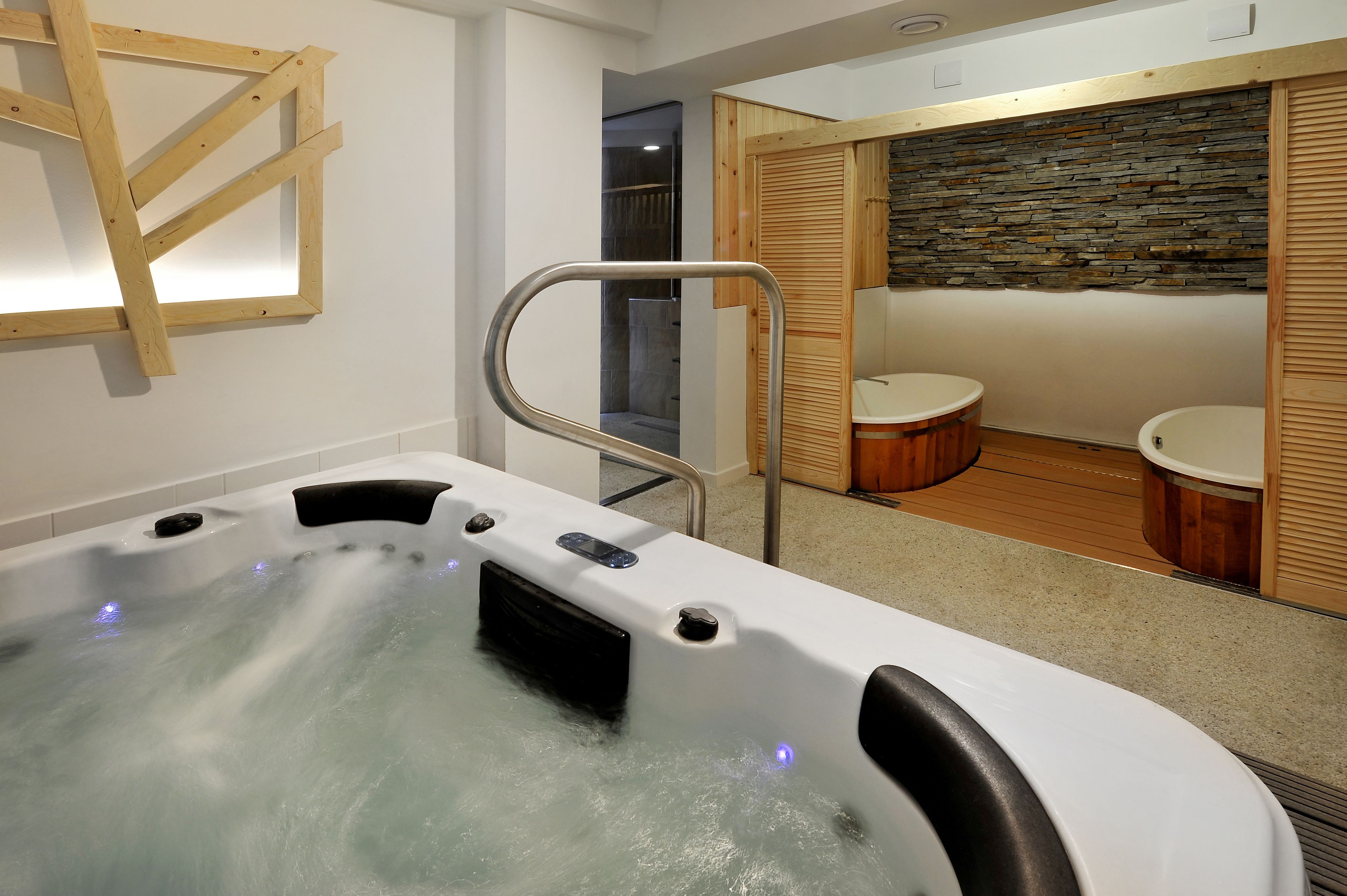 Ein Badezimmer mit Whirlpool, Holzboden und einer Steinwand.