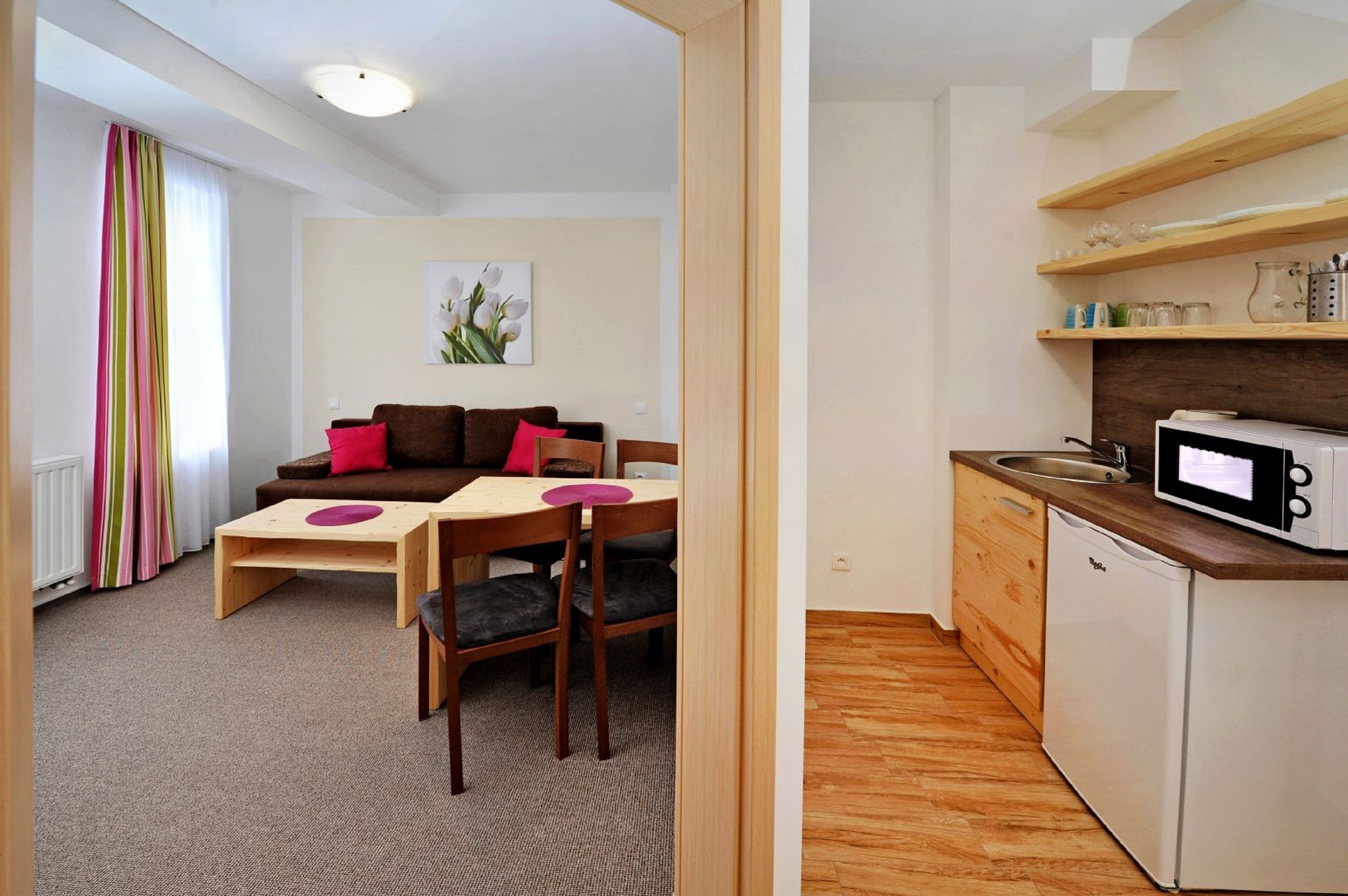 A compact living space with a kitchenette, a dining area, and a sofa with cushions.