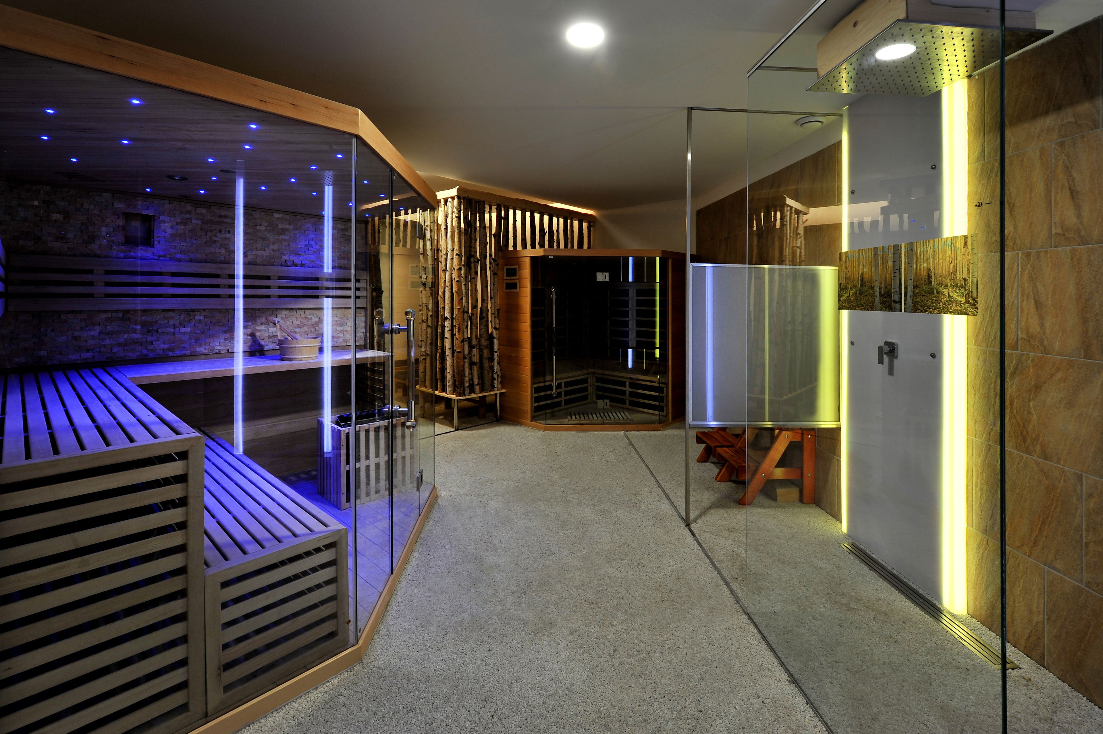 A modern spa area with a wooden bench, glass partitions, and a stone wall.