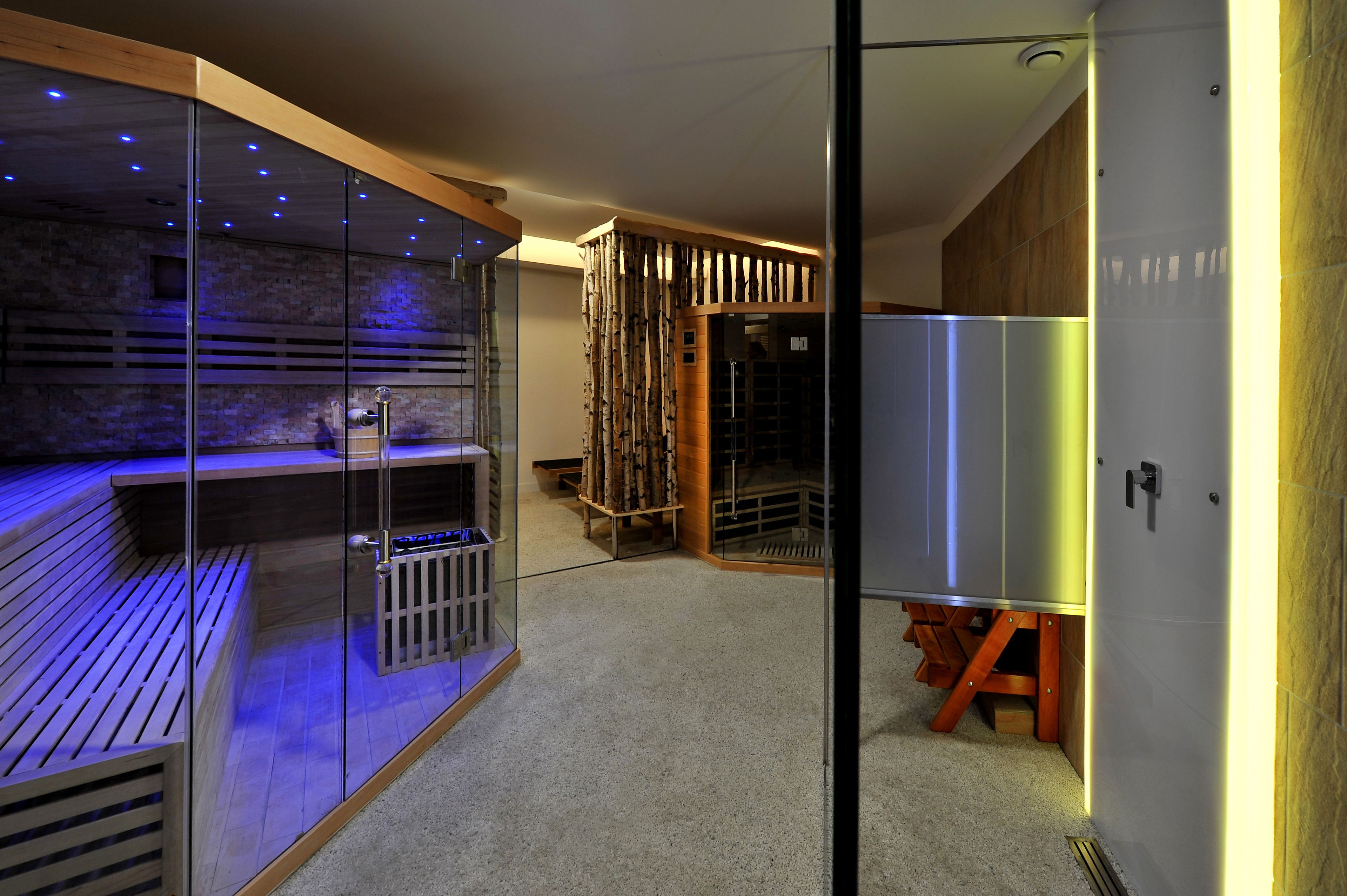 A modern spa area with a wooden bench, glass partitions, and a sauna.