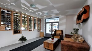 A modern interior with a wine rack, a coffee table, a sofa, and a large window. - Apartmány Belveder (Vysoké Tatry)