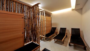A room with wooden sliding doors, a birch tree wall, and three wooden beds with black mattresses. - Apartmány Belveder (Vysoké Tatry)
