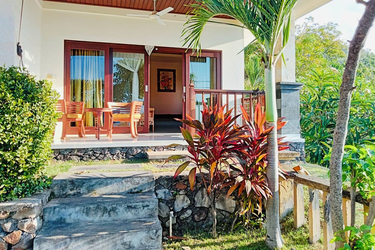 A house with a wooden deck, outdoor seating, and a stone staircase leading to the entrance.