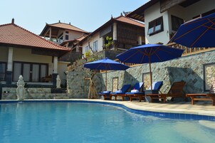 Una piscina al aire libre, sillones reclinables de piscina