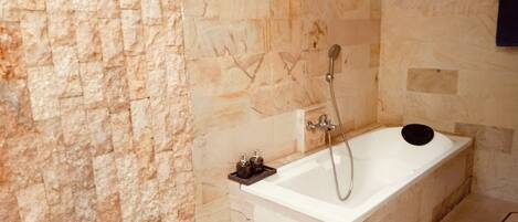 Un baño moderno con pared de piedra, una bañera y una ducha.