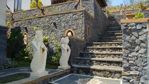 Una escalera de piedra con estatuas en la base, que conduce a un edificio de fachada de piedra y un balcón.