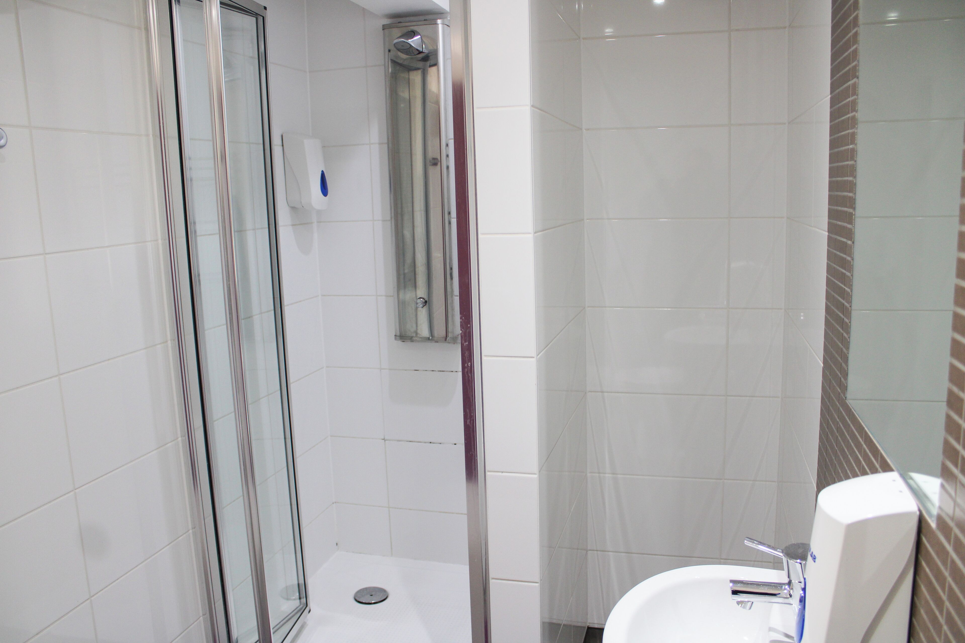 Une salle de bain moderne avec une douche à parois de verre, un lavabo blanc et un miroir.