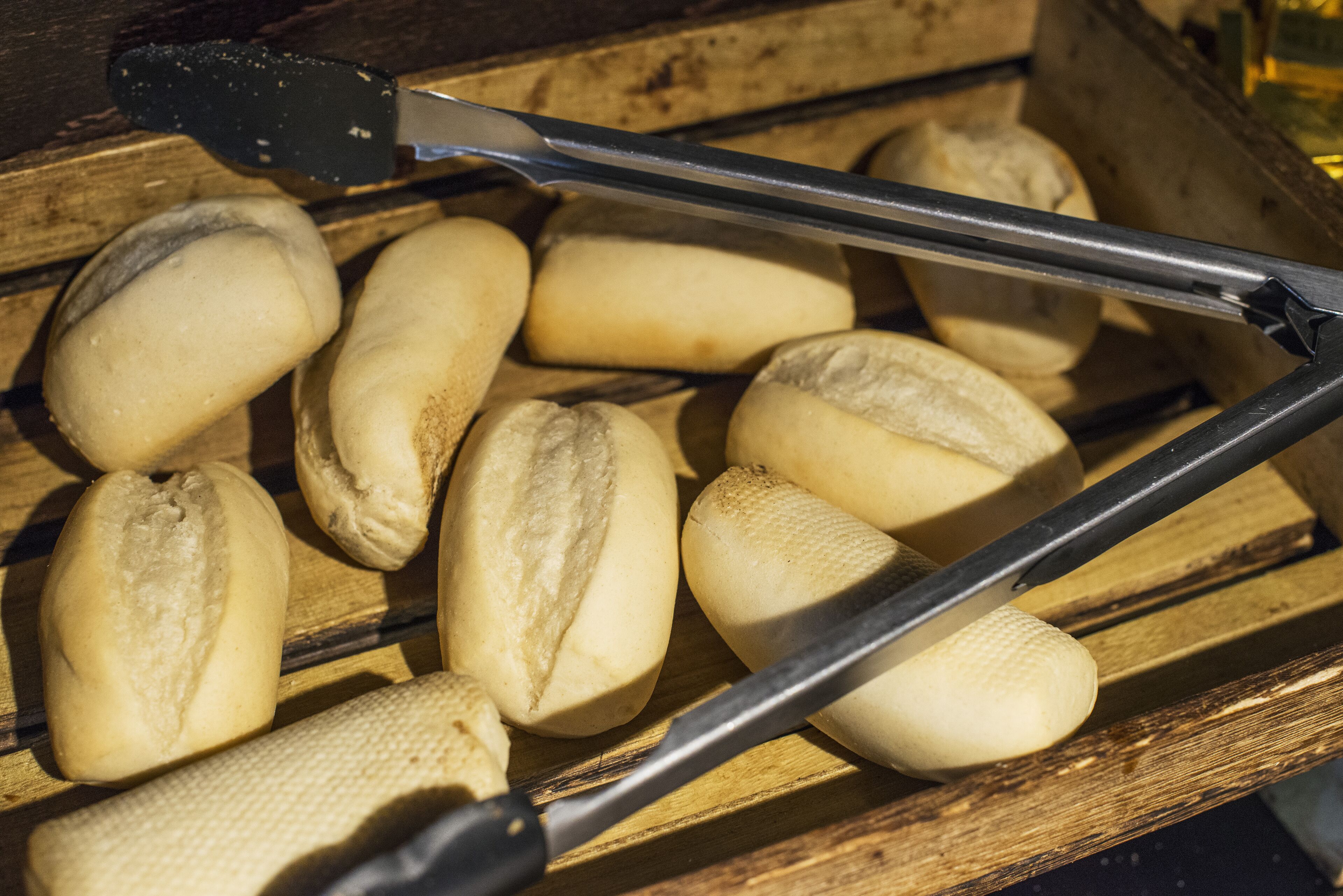 A wooden tray with several bread rolls.