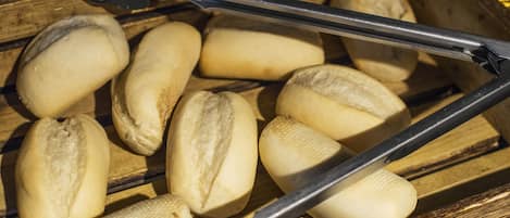 A wooden tray with several bread rolls.