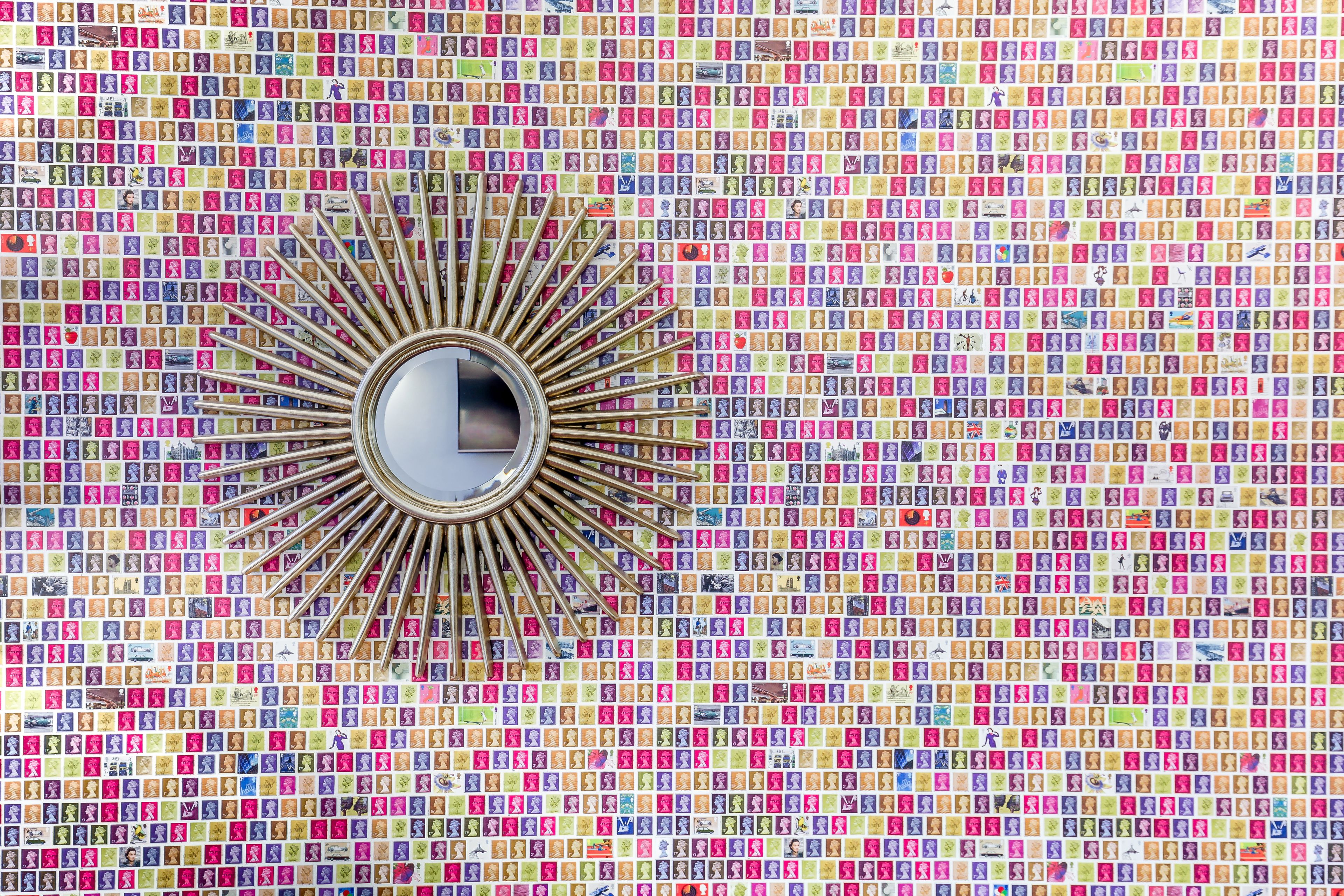 A sunburst mirror surrounded by a mosaic of colorful photographs.