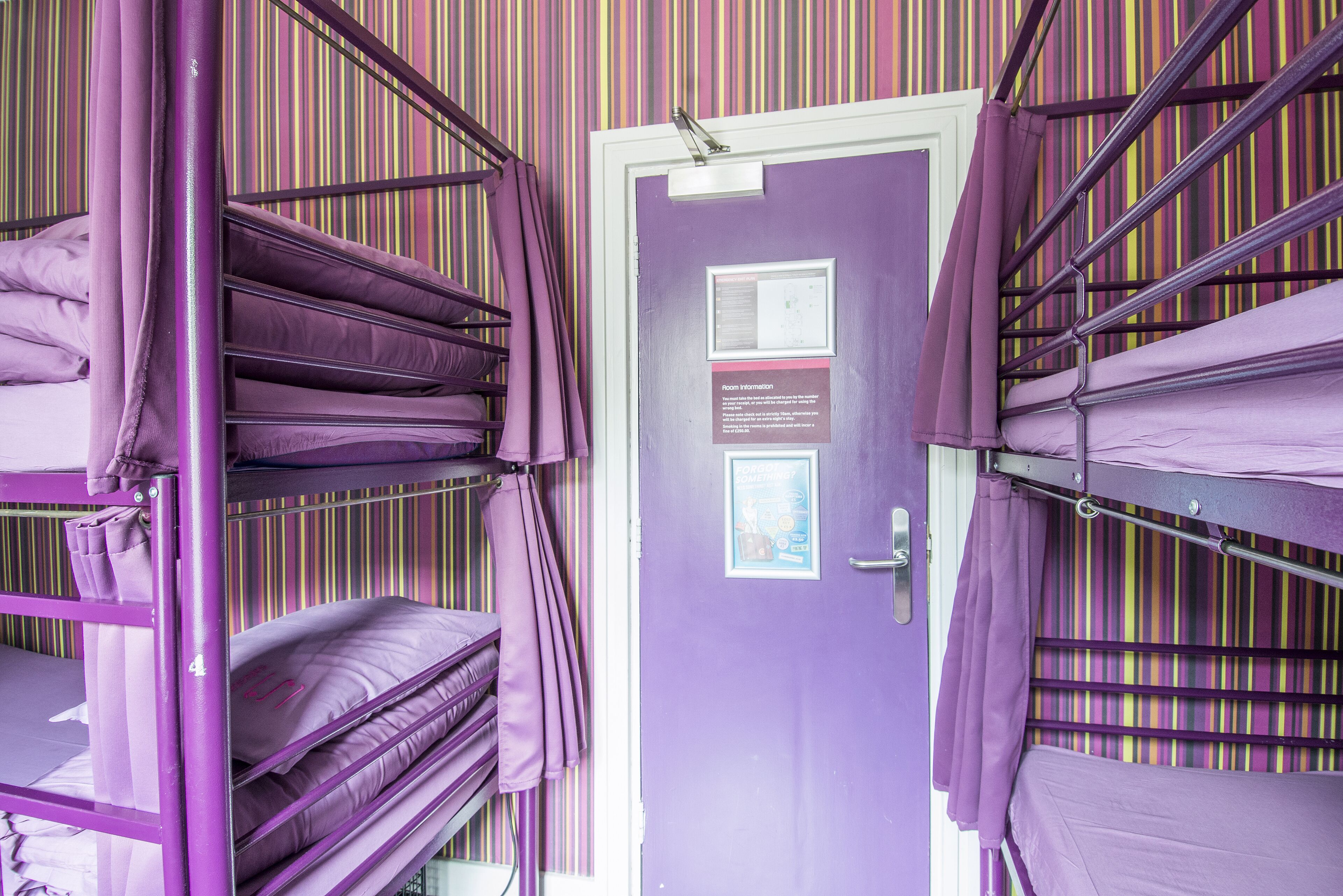 A purple room with bunk beds, a door with a sign, and striped wallpaper.