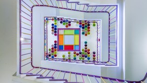 Una escala espirall amb un disseny geomètric colorit al centre i una barana morada.