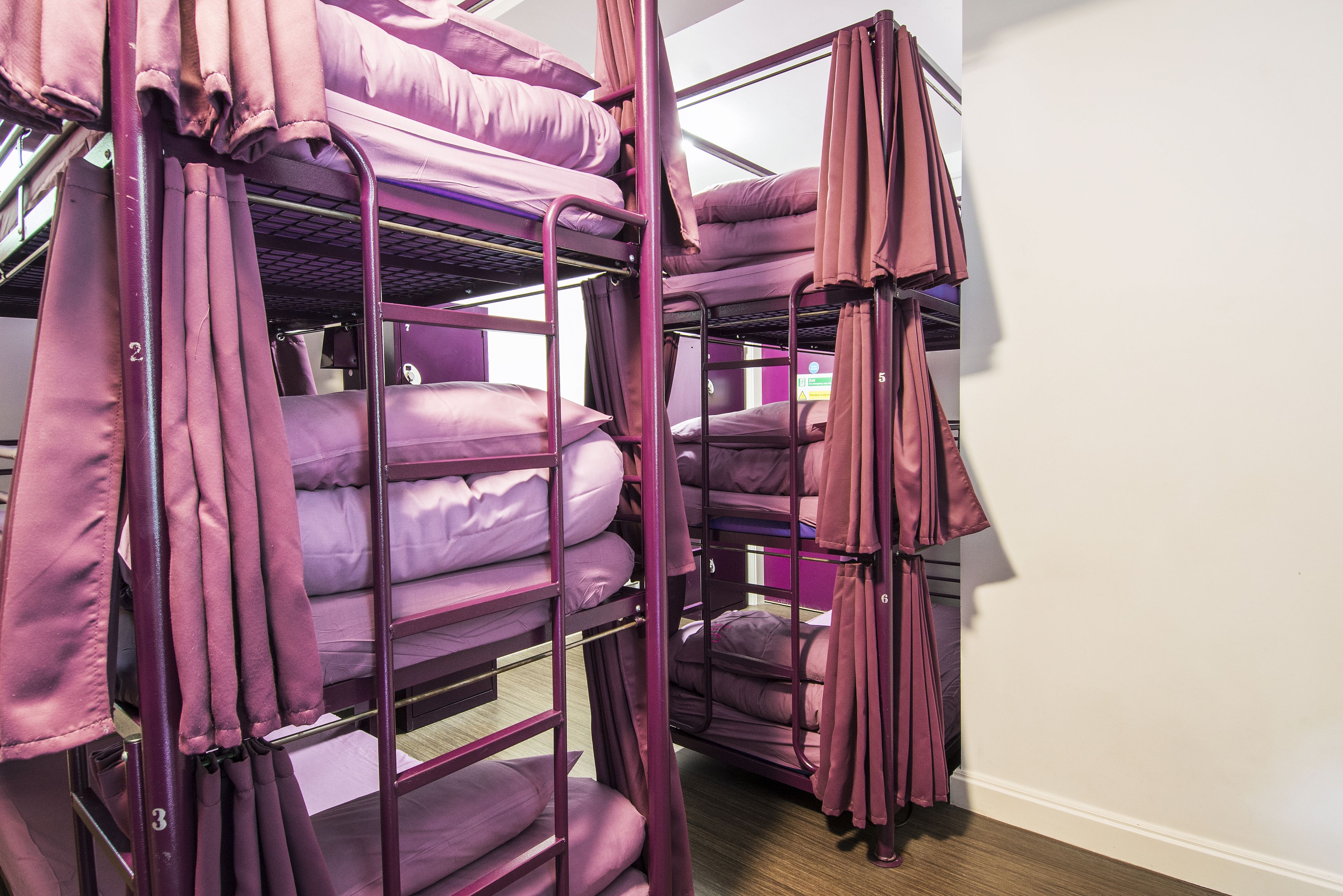 Camera con letto a castello, biancheria viola e tende.