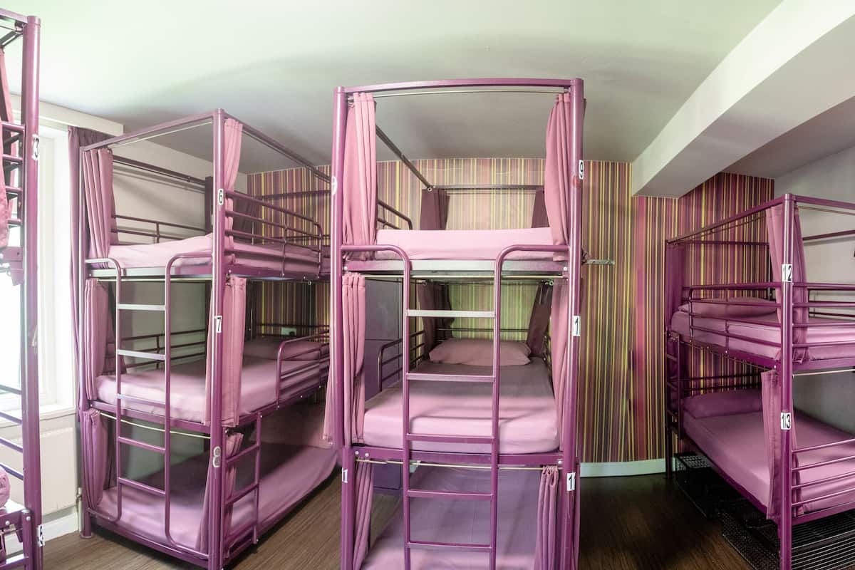 Bunk beds in a room with striped wallpaper and a window.