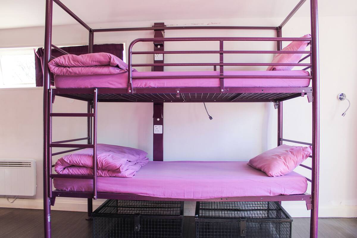 A bunk bed with two levels, each with a mattress and pillows.