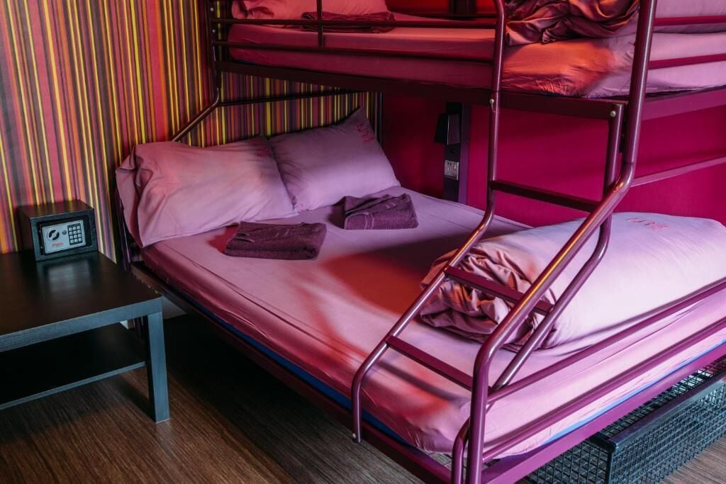 Une chambre avec un lit superposé, une petite table et une prise de courant.