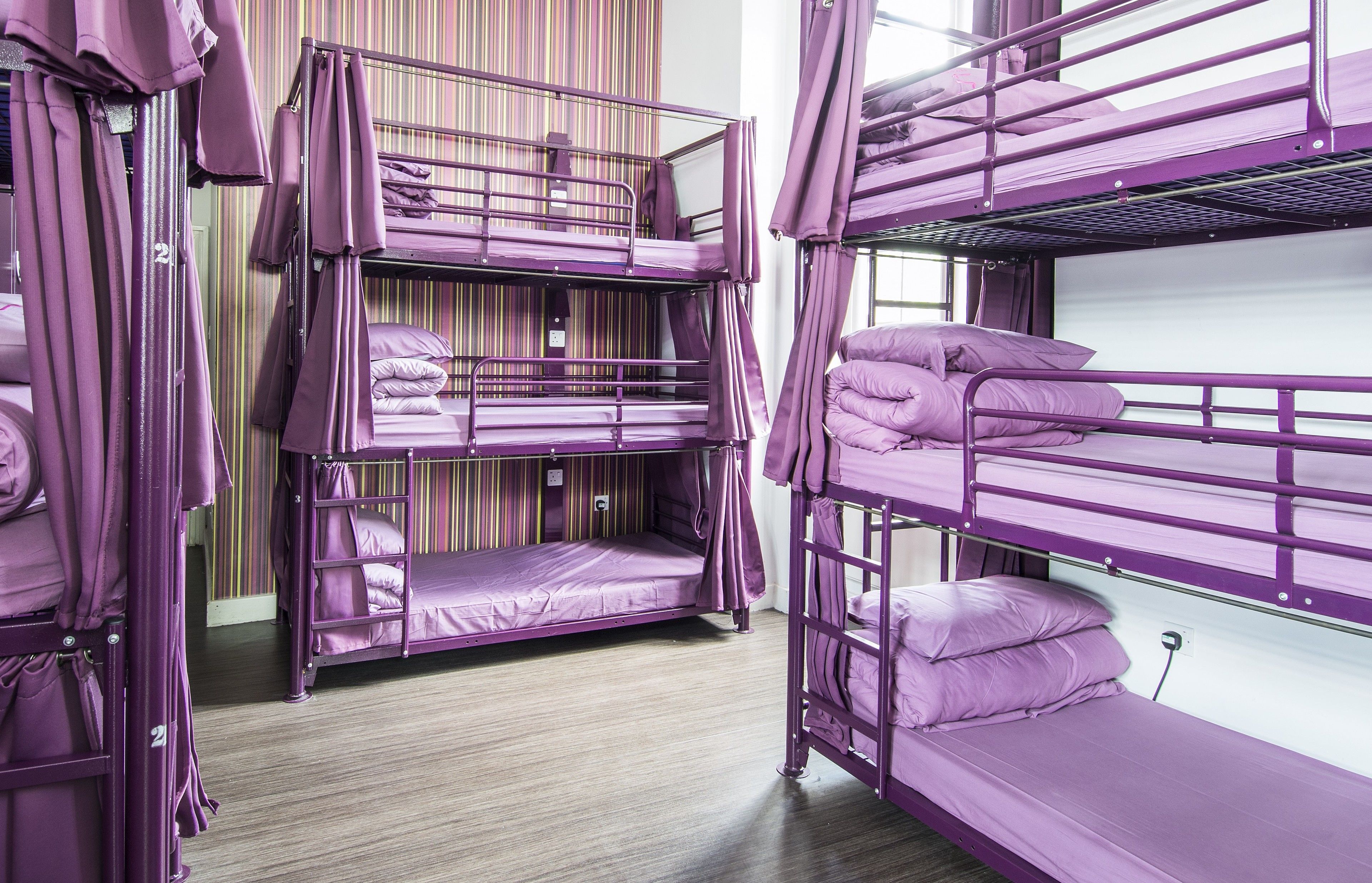 A room with bunk beds, a striped wall, and a wooden floor.