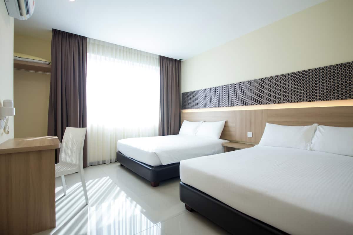 A hotel room with two beds, a desk, a chair, and a large window with curtains.