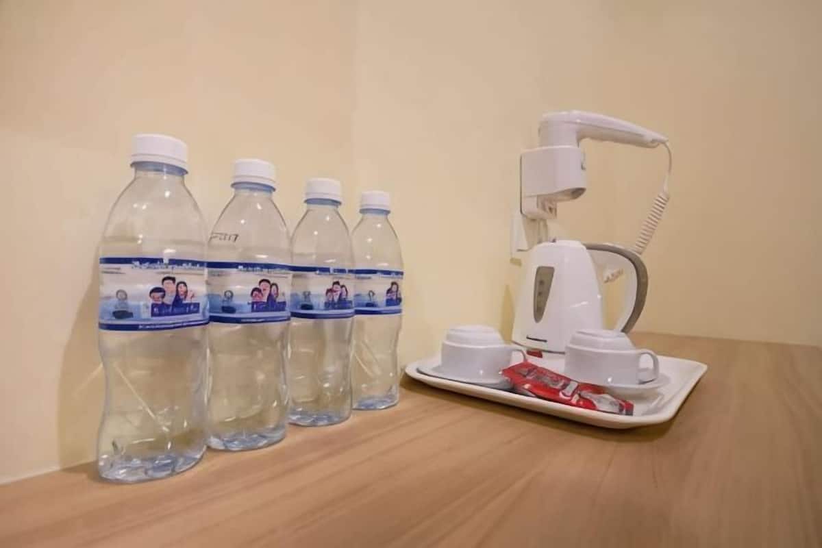 Four water bottles, a coffee maker, and a tray with a red cup on a wooden table.